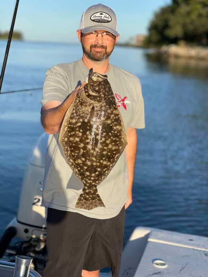 A man is standing on a boat holding a large fish.