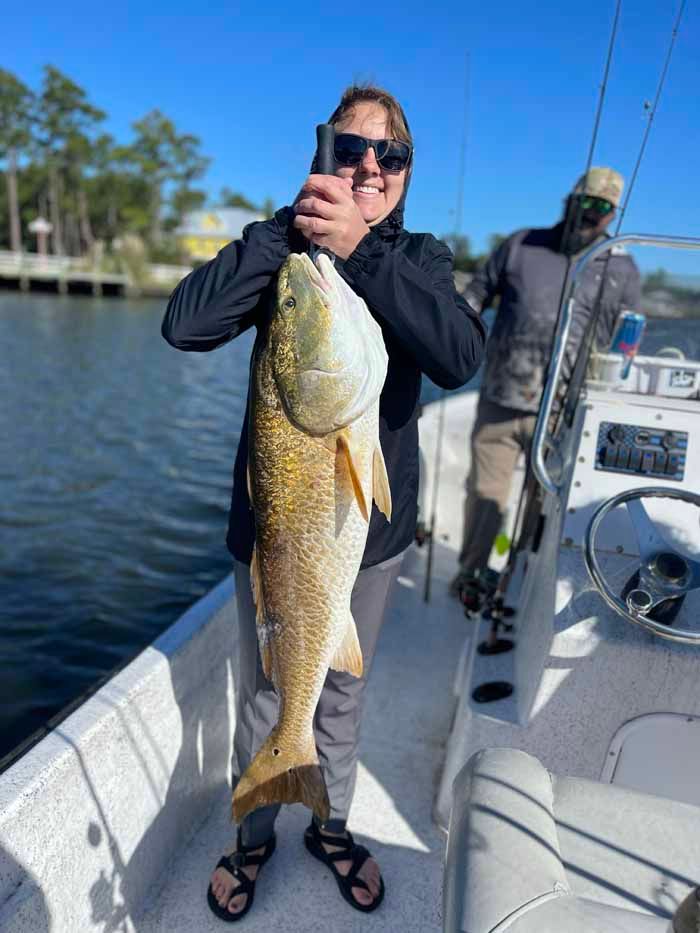 A man is holding a large fish on a boat.