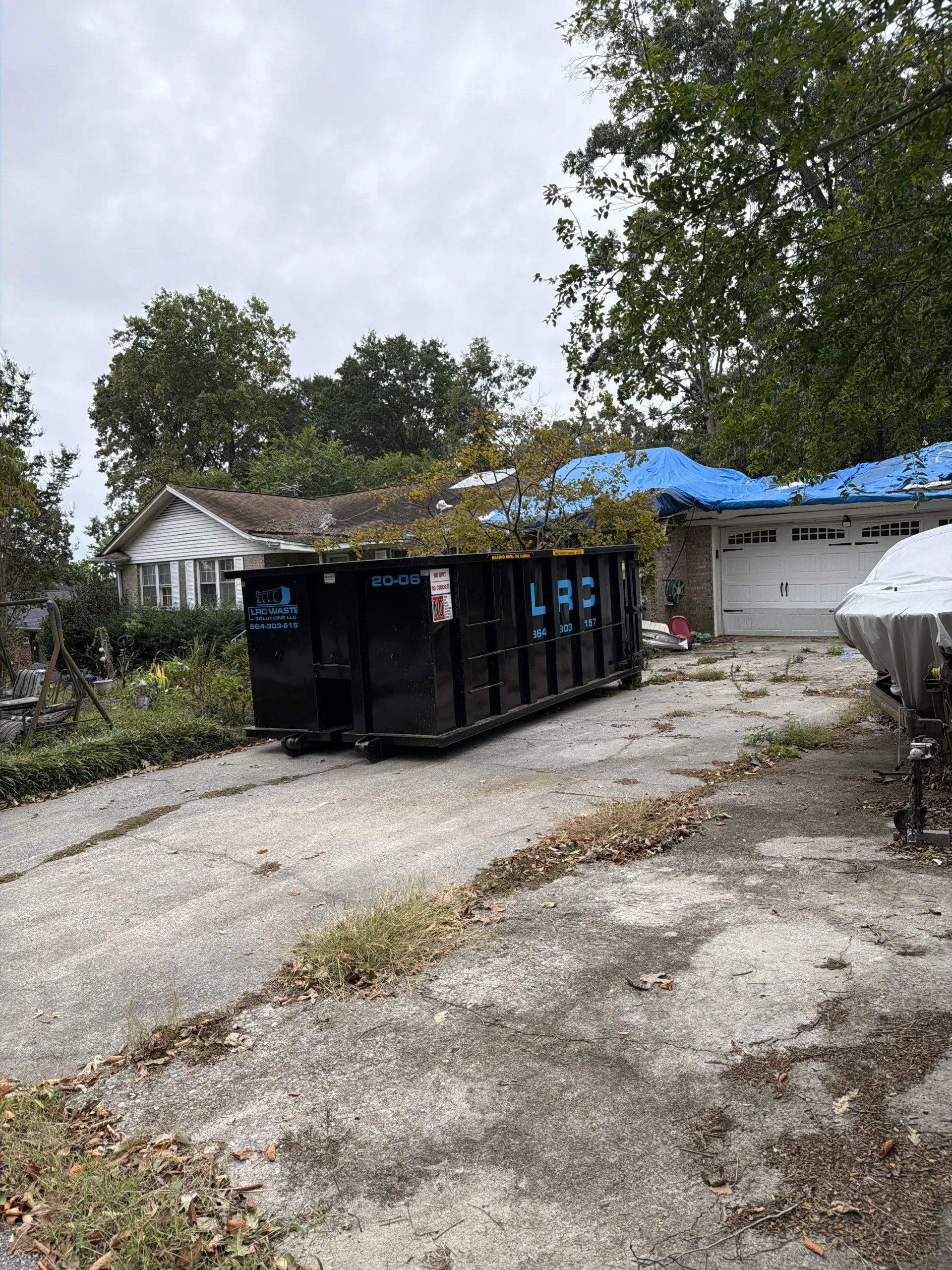 A dumpster is sitting on the ground next to a trailer.