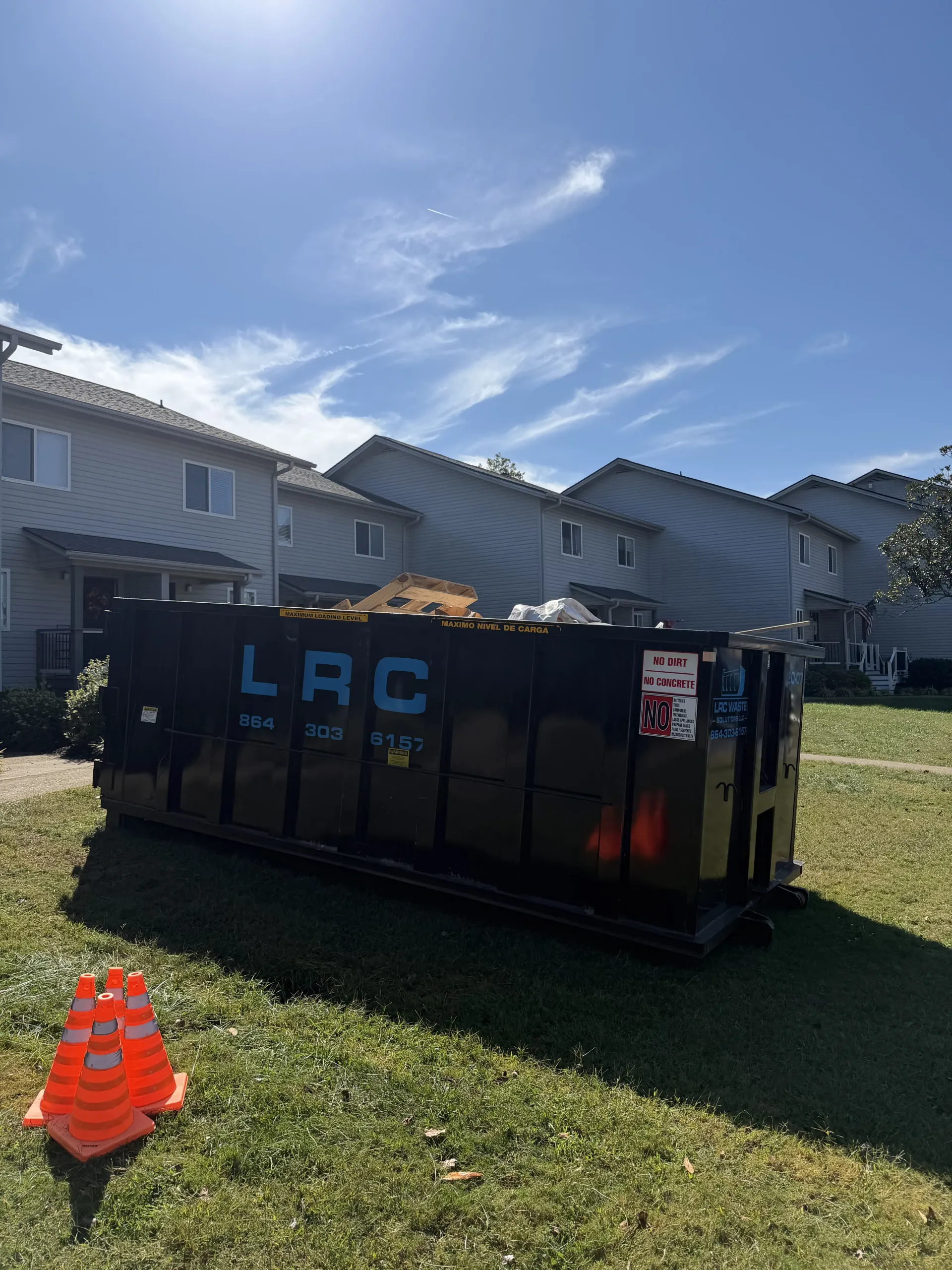 A dumpster is parked in front of a brick building.