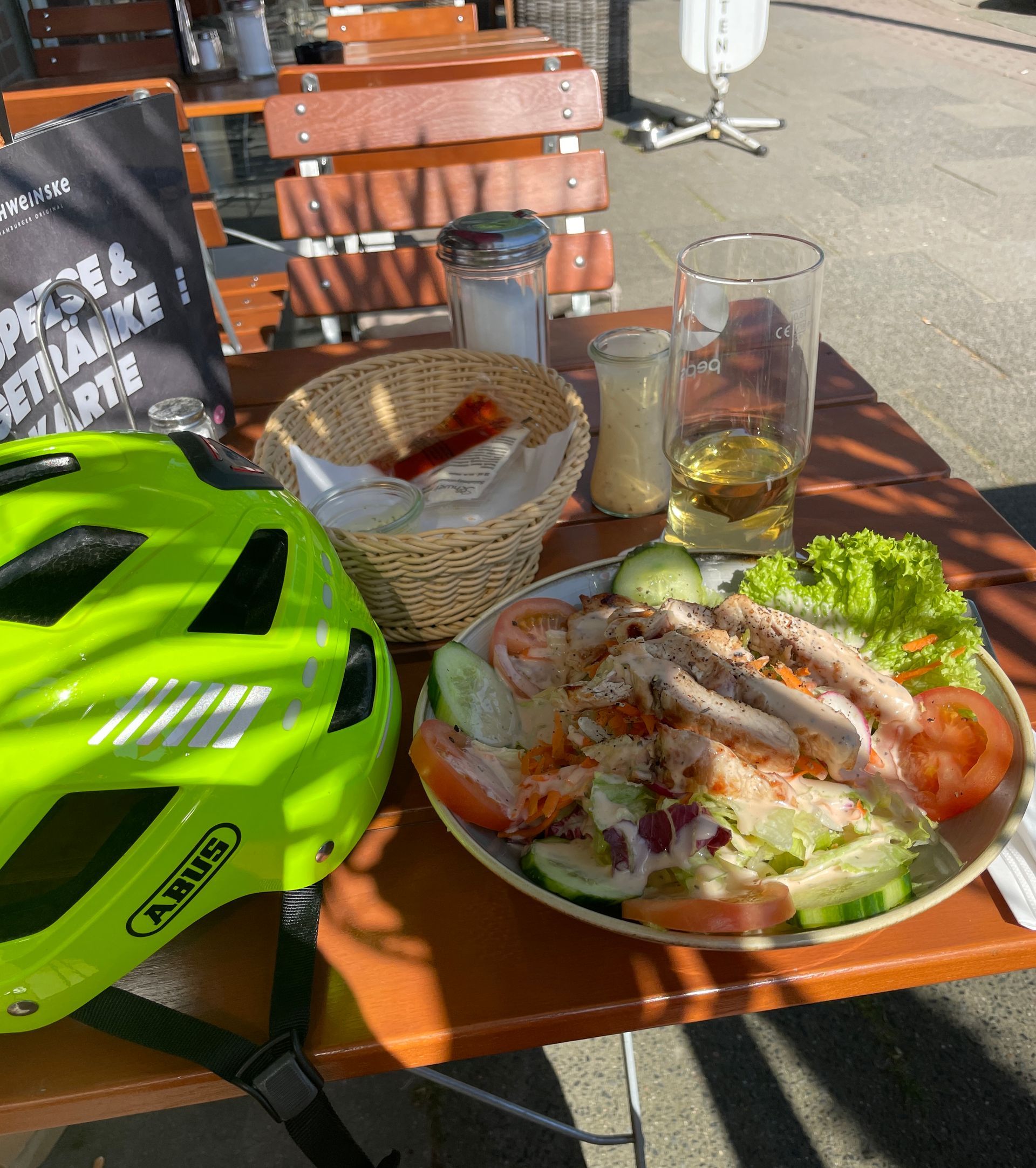 Neongelber Fahrradhelm, Apfelschorle im Glas, gemischter Salat mit gegrillter Pute 