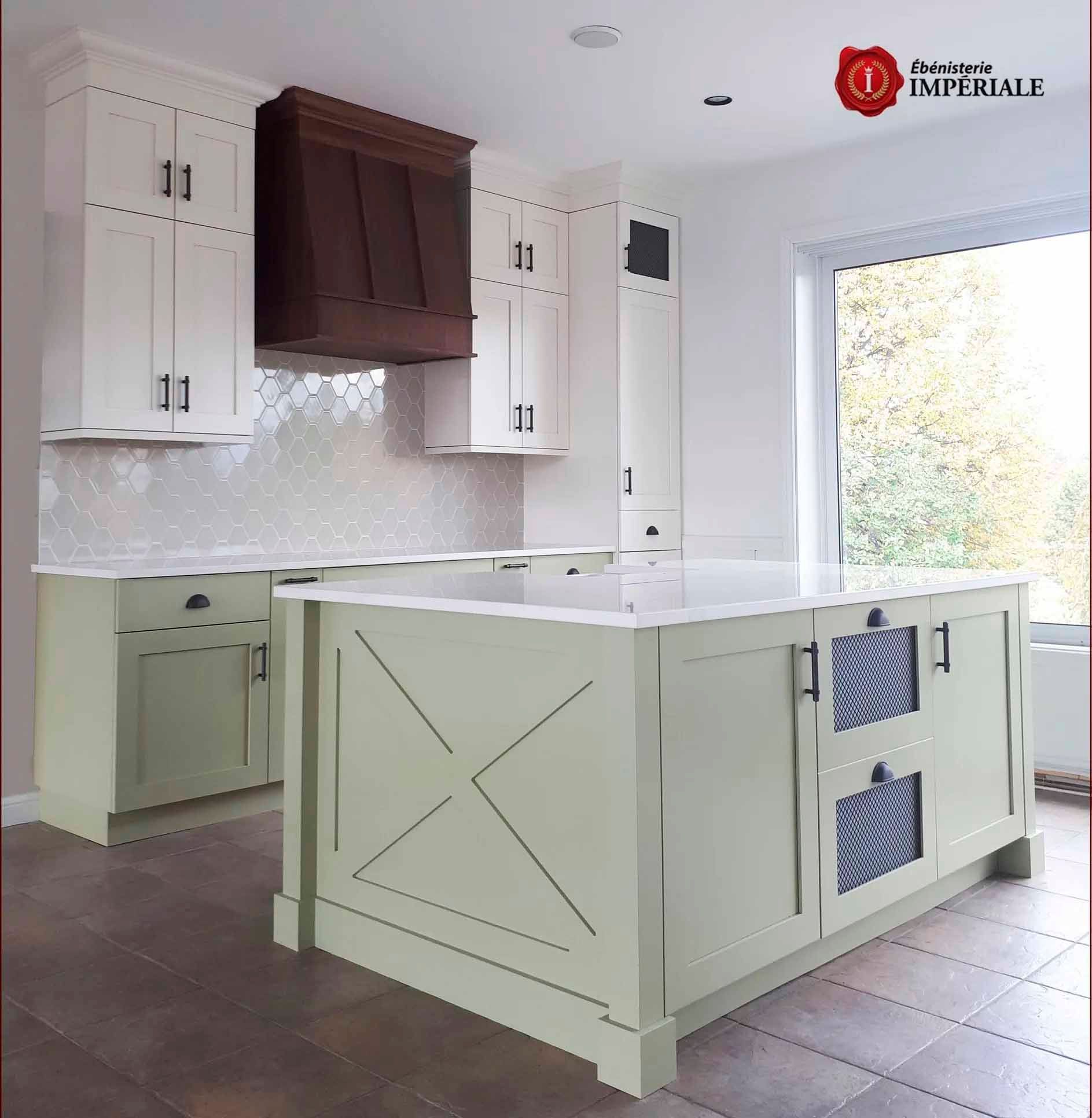 Cuisine avec placards vert clair, plans de travail blancs et hotte aspirante marron foncé.