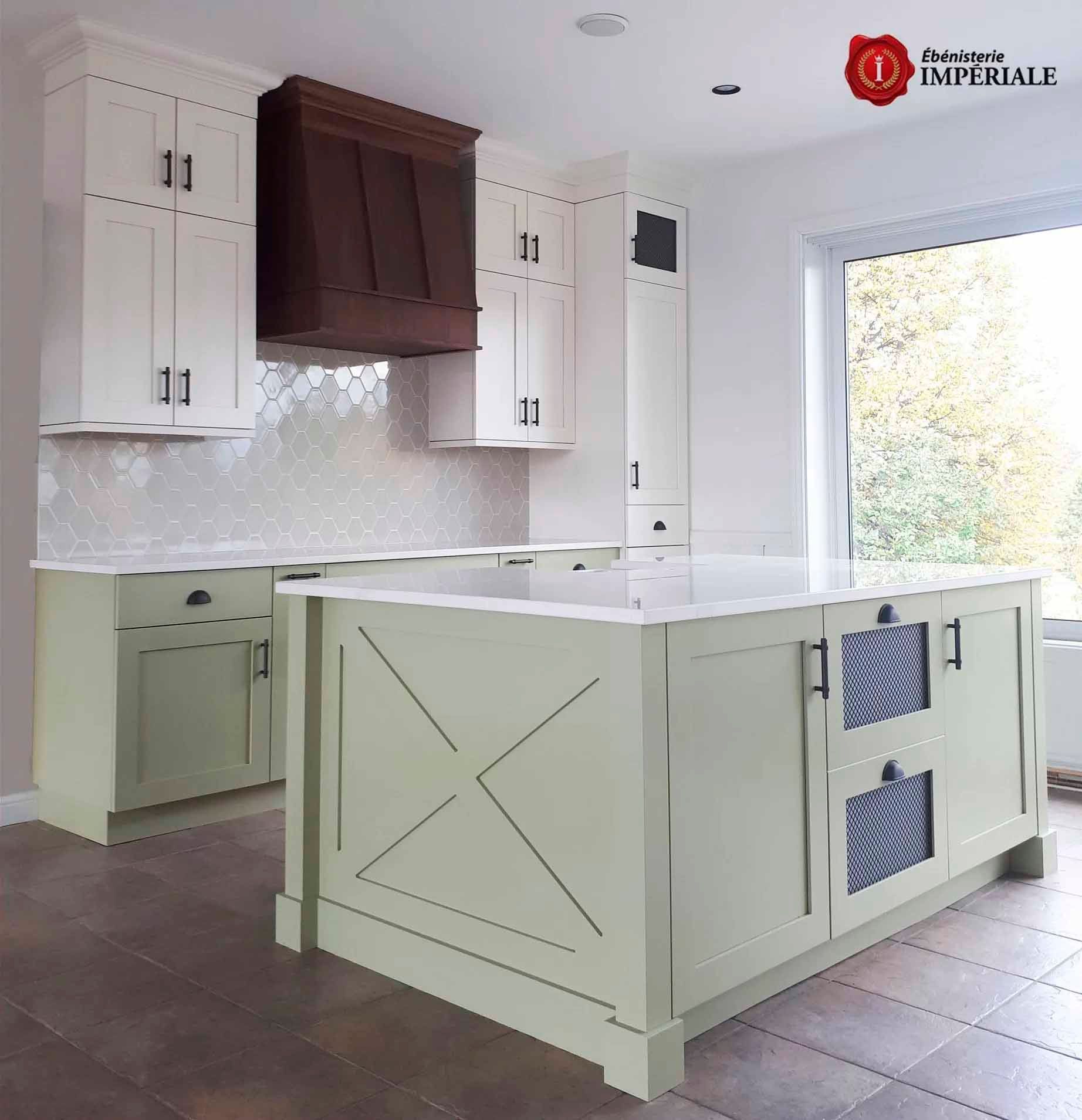 Cuisine avec placards vert clair, plans de travail blancs et hotte en bois foncé.