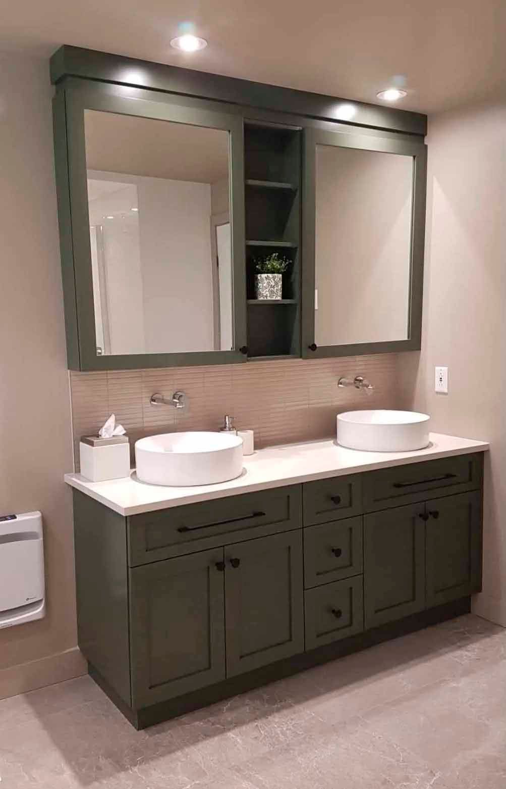 Meuble-lavabo vert foncé avec deux lavabos blancs, miroirs et rangements.