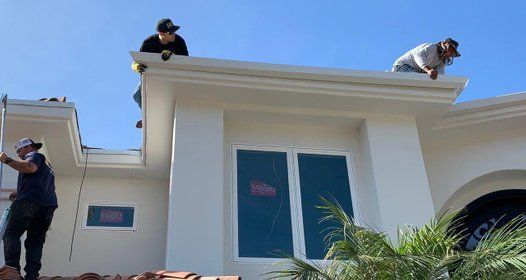 two men are working on the roof of a house .
