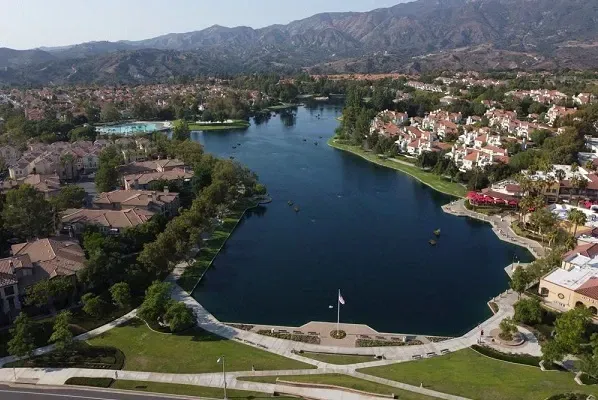 an aerial view of a lake in a residential area with mountains in the background .