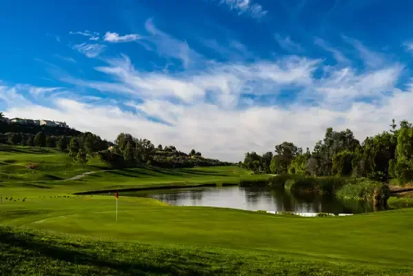 a golf course with a pond in the middle of it .