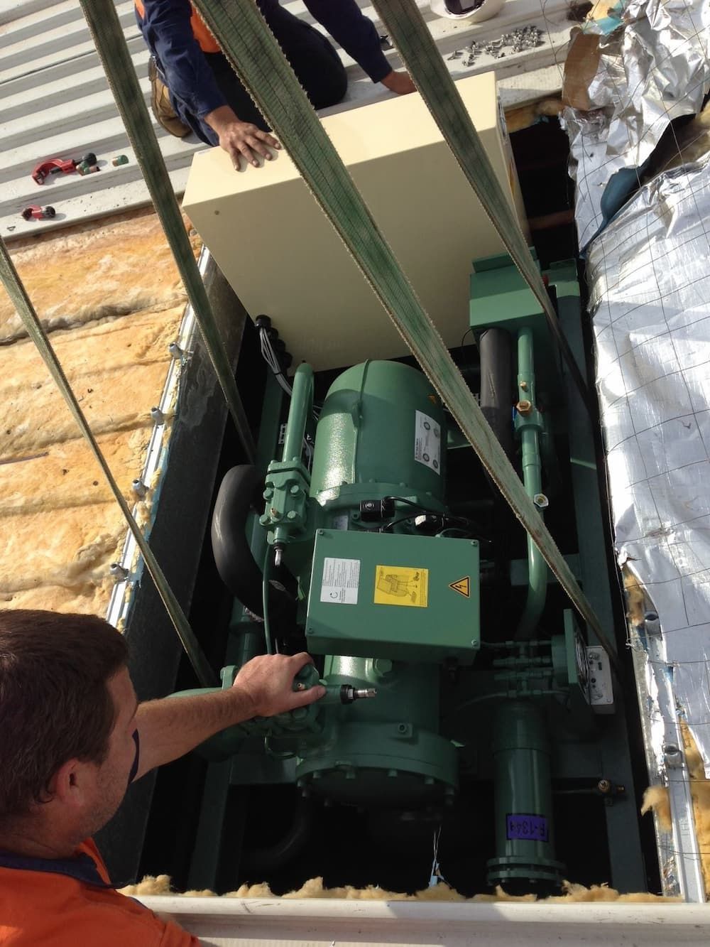 A Man Is Working On A Green Machine In A Warehouse — Mackies In Taree, NSW