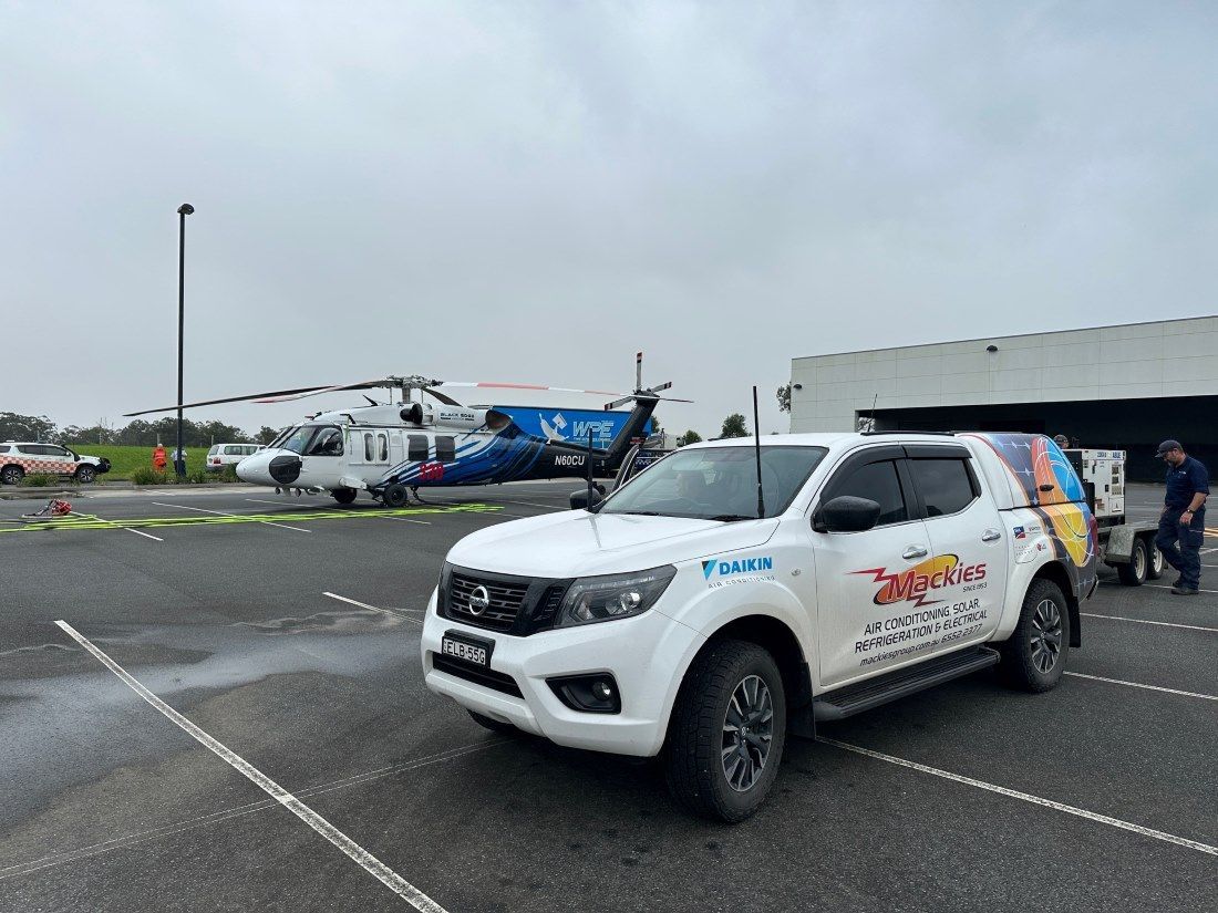 White Nissan Truck With Logo Parked Near A Helicopter On A Tarmac — Mackies In Coffs Harbour, NSW