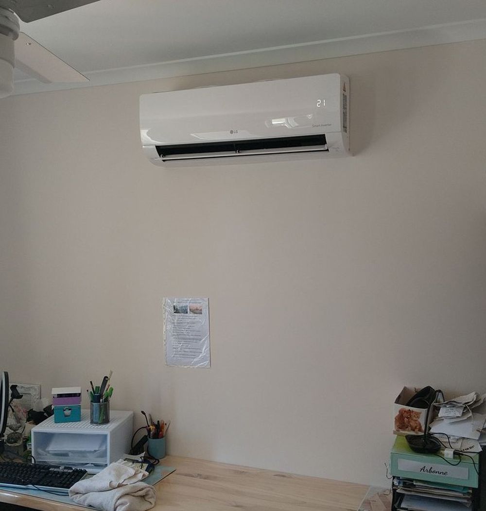 Air Conditioning Unit Mounted On A Beige Wall Above A Desk With Office Supplies — Mackies in Taree, NSW