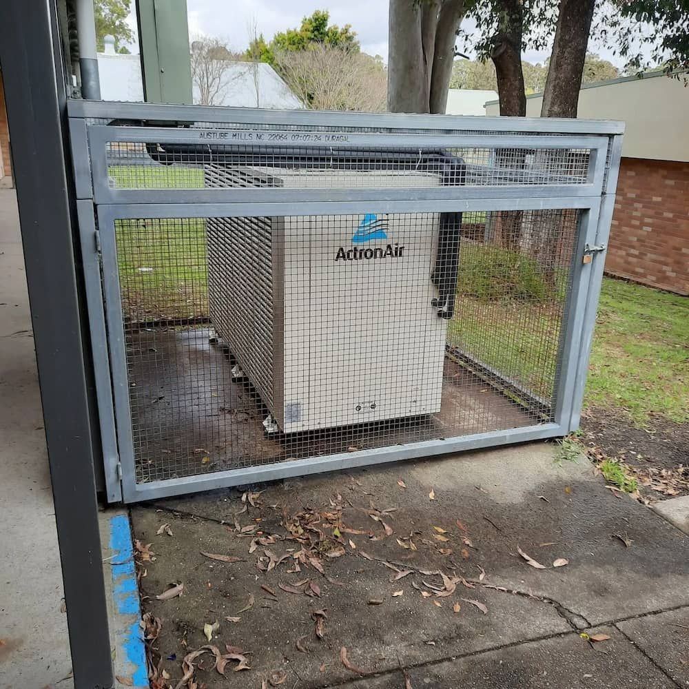 An Air Conditioner Is Sitting Inside Of A Metal Cage — Mackies In Taree, NSW