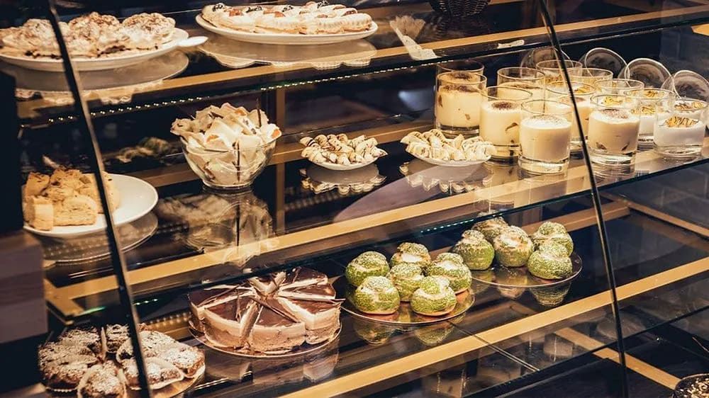 A Glass Display Case Filled With Lots Of Desserts In A Bakery — Mackies In Taree, NSW