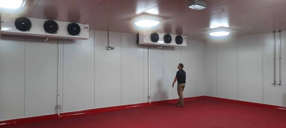 A Man Is Standing In A Large Room With A Red Floor — Mackies In Taree, NSW
