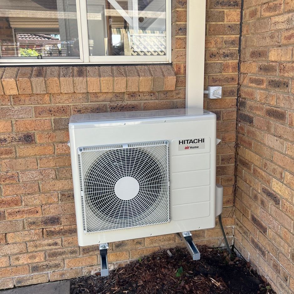 A Hitachi Air Conditioner Is Mounted On The Side Of A Brick Building — Mackies In Taree, NSW