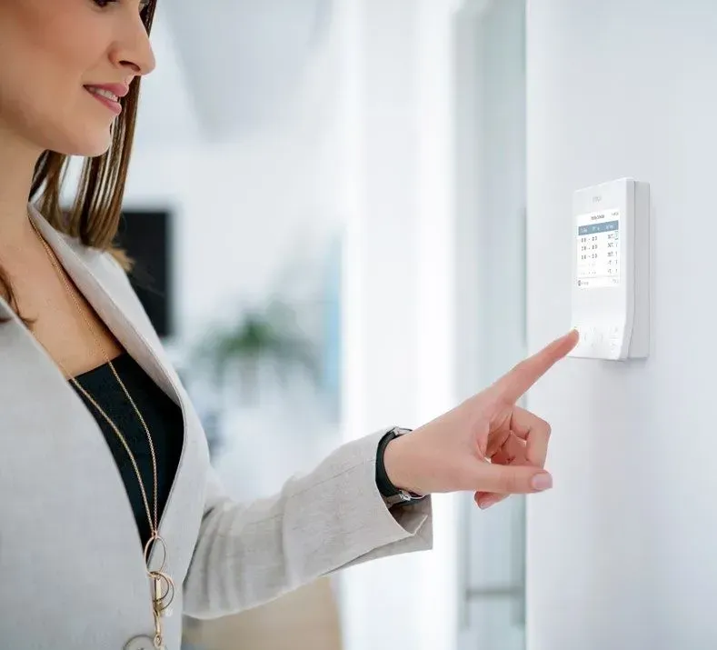Woman In Blazer Touches A White Wall-mounted Control Panel, Smiling — Mackies in Taree, NSW