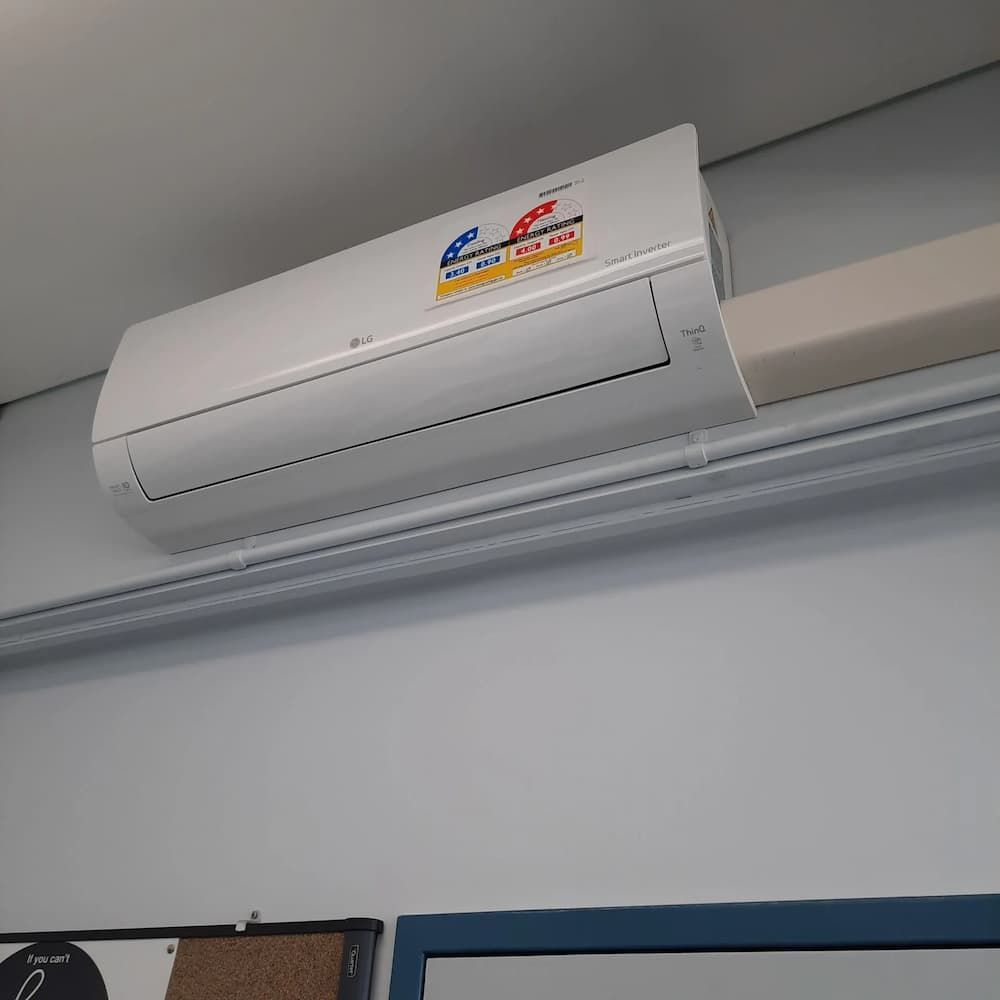 A White Air Conditioner Is Hanging From The Ceiling In A Room — Mackies In Taree, NSW