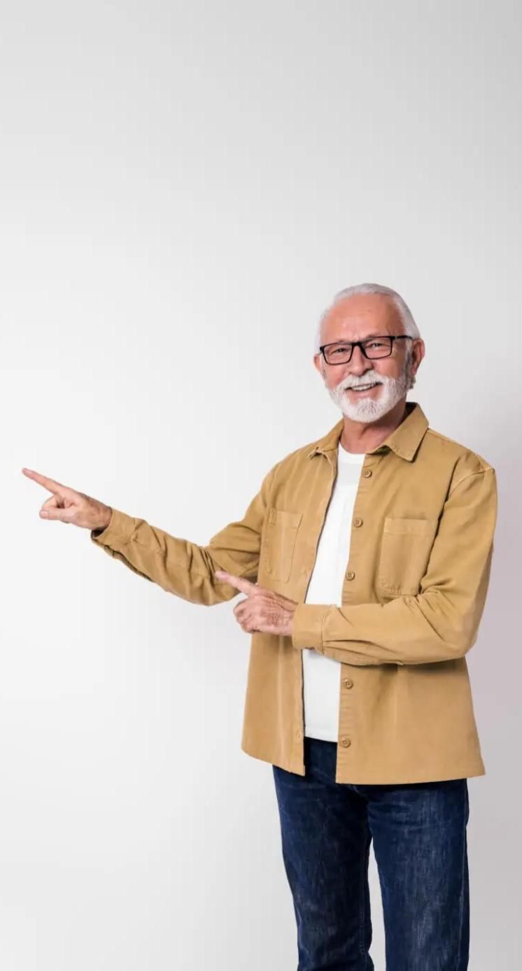 Smiling Senior Man With Glasses Points Left, Wearing Tan Shirt — Mackies in Taree, NSW