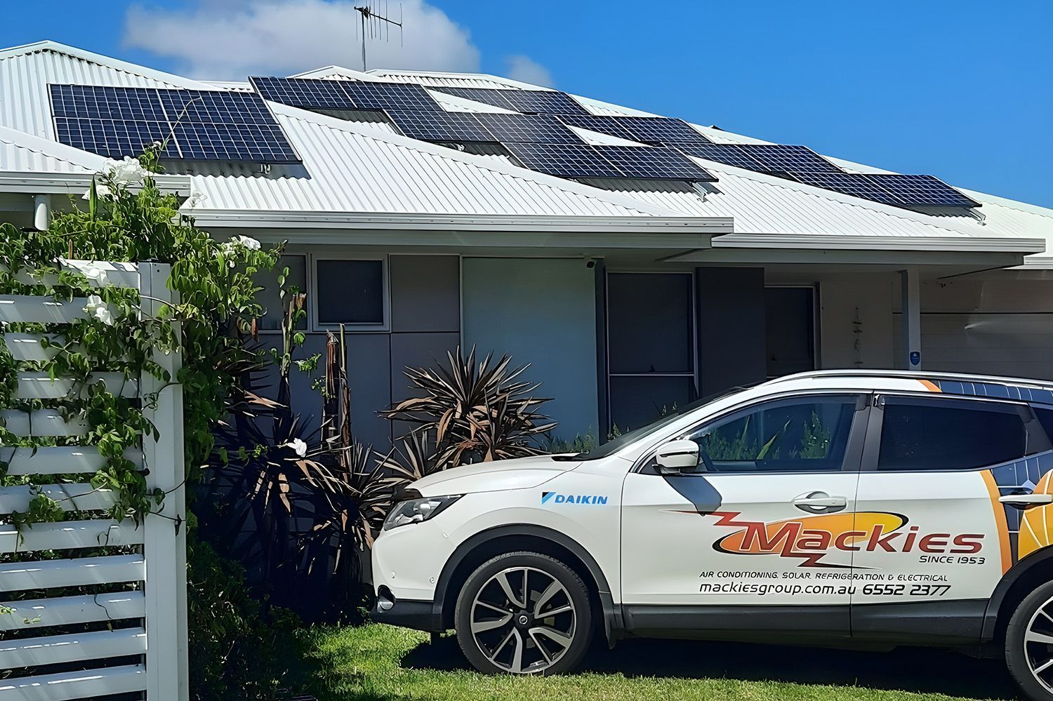 A Mackies' Electrical Service Vehicle Is Parked In A Residential House With Roof Solar Panels