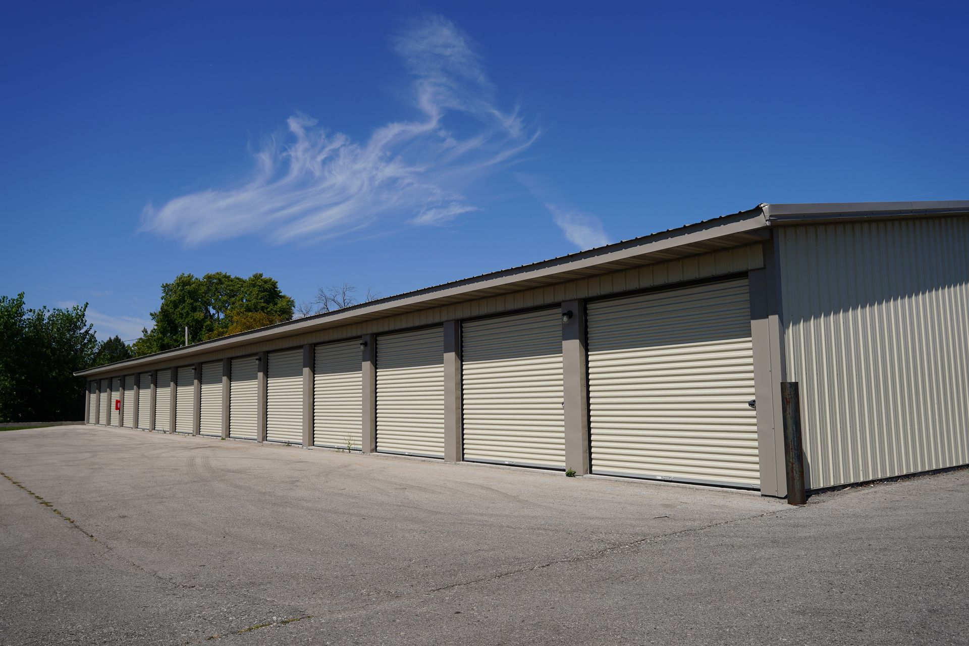 Storage units in a row; tan doors, light gray building, blue sky.