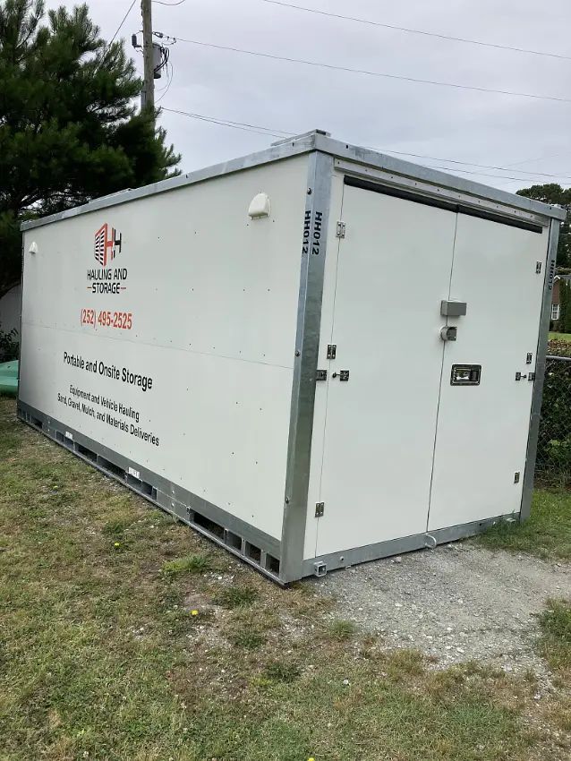 White portable storage unit on grass, labeled with company name and contact info.