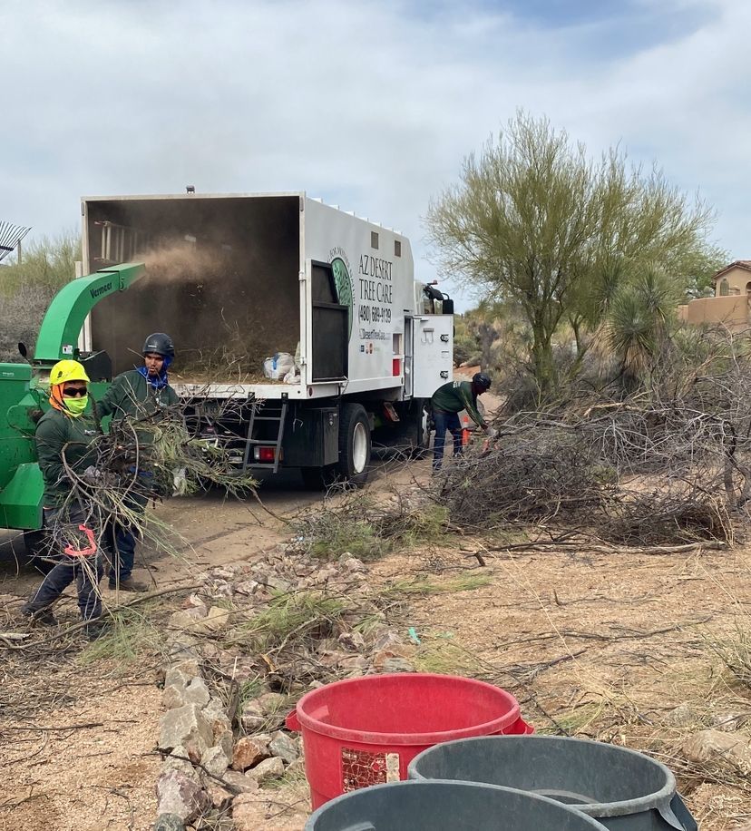 Workers chipping brush; a truck with a chipper; a desert setting.