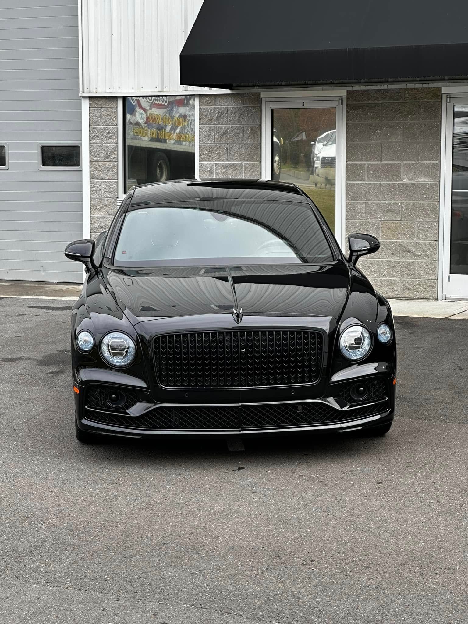 Black sports car parked in front of a building entrance