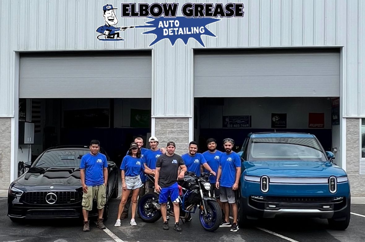 A person wearing black gloves is cleaning a black car with a blue cloth.