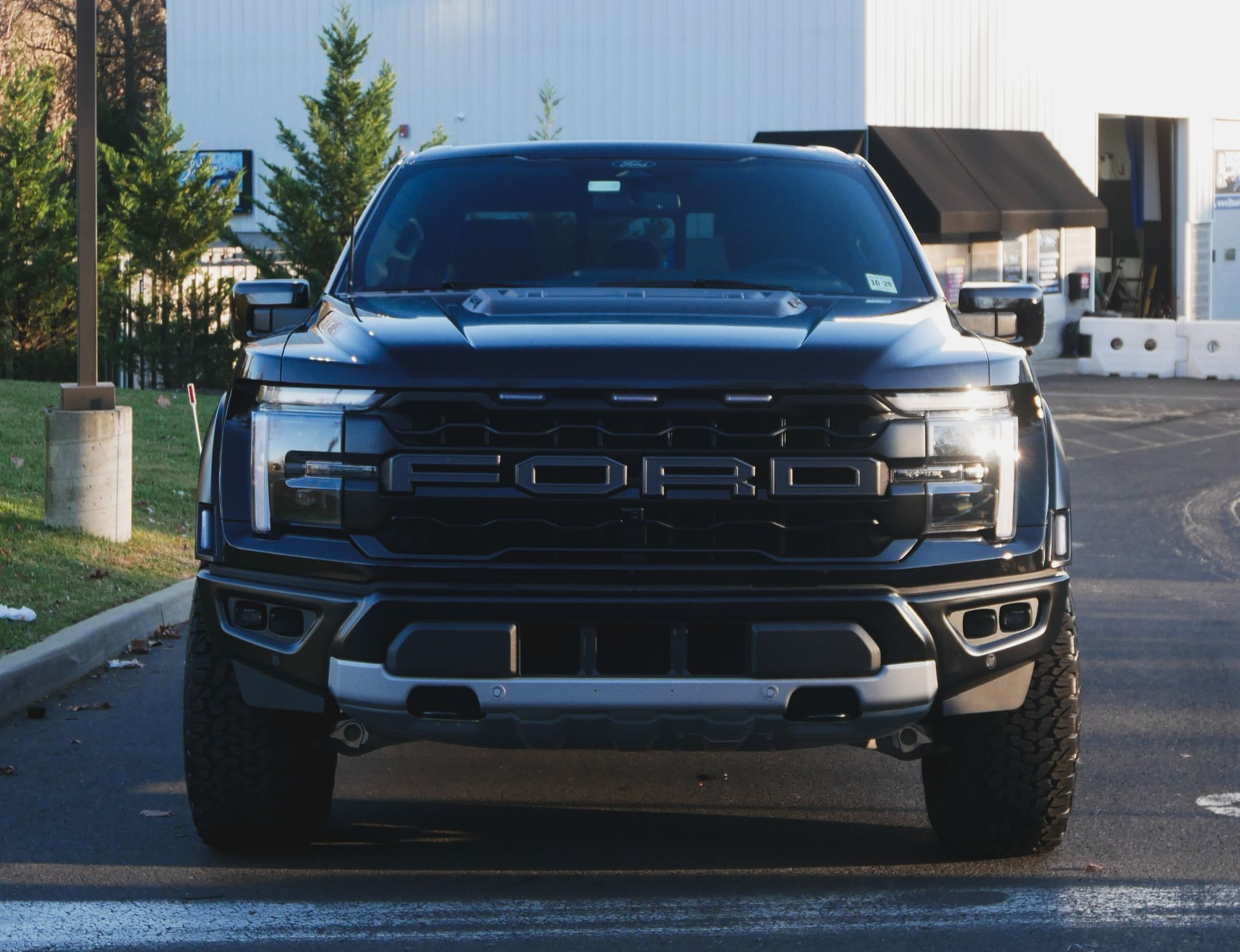 Black BMW car parked in front of a wooden fence.