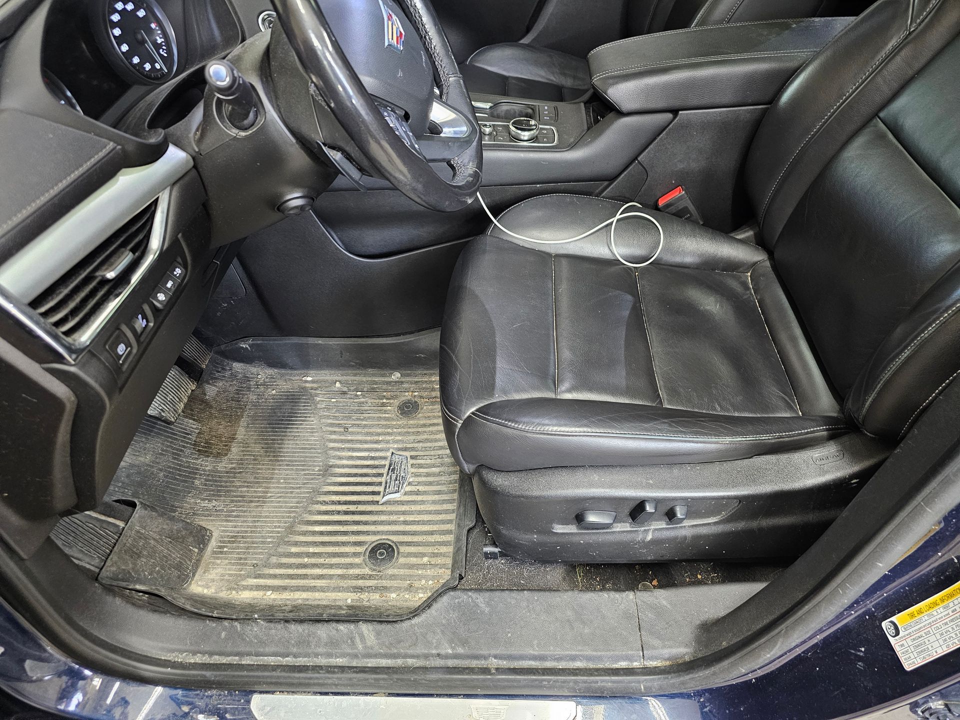 The inside of a dirty car with a steering wheel and seats.
