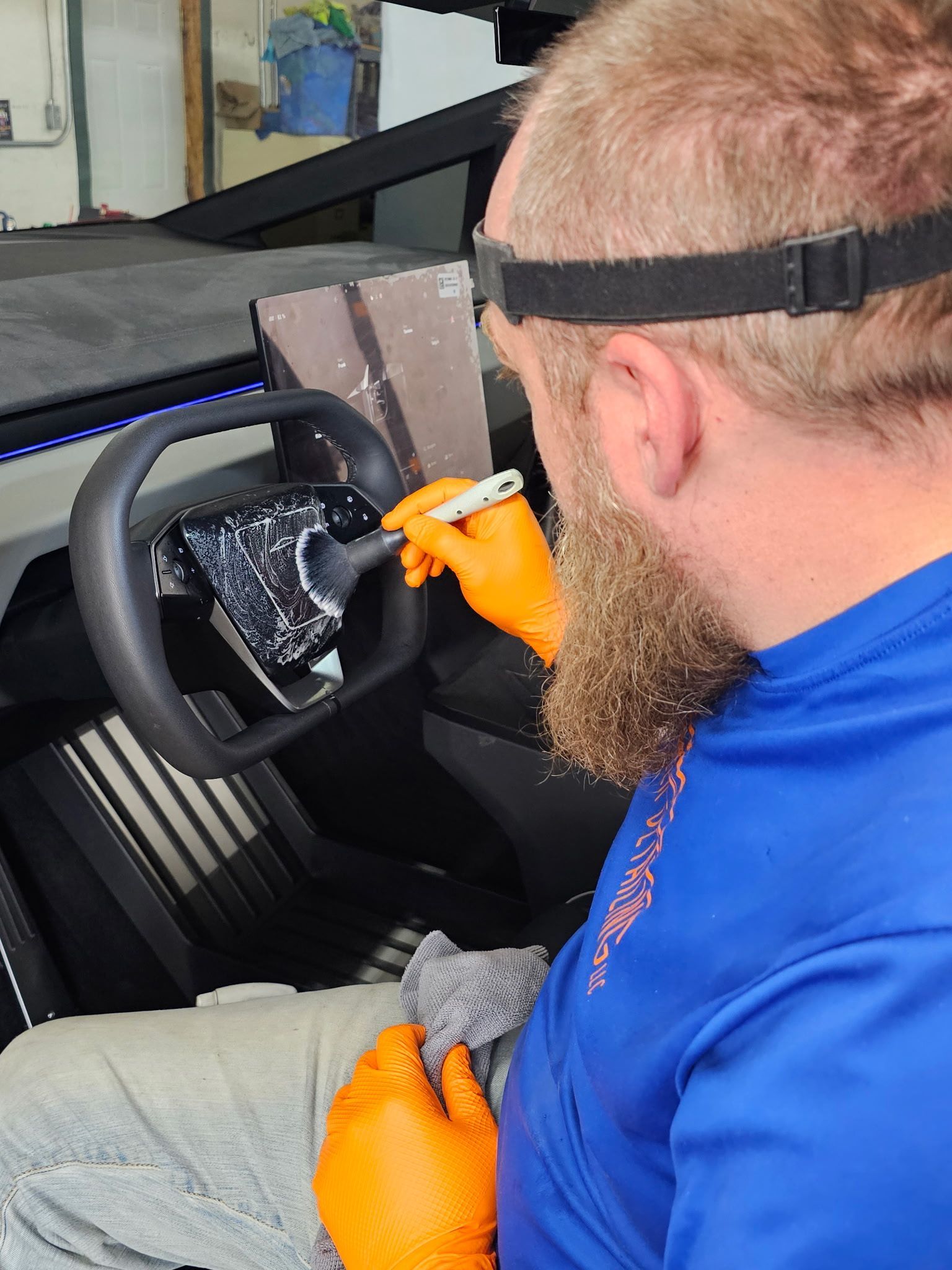 A man with a beard is cleaning the steering wheel of a car.