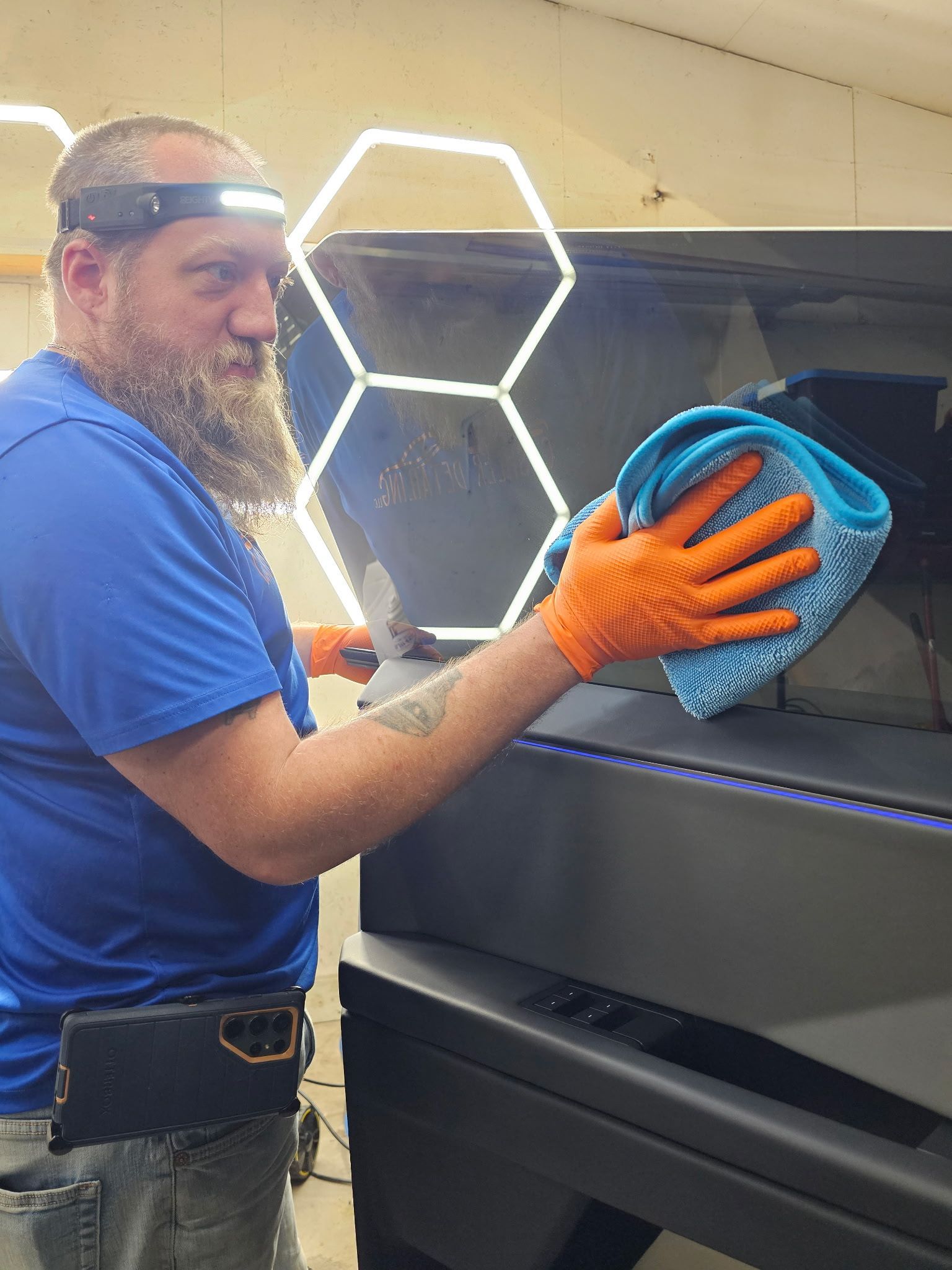 A man with a beard is cleaning a machine with a cloth.