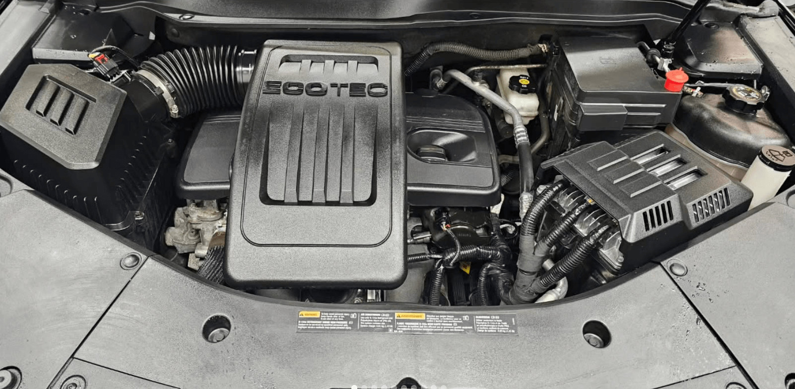 A close up of the engine of a car with the hood open.