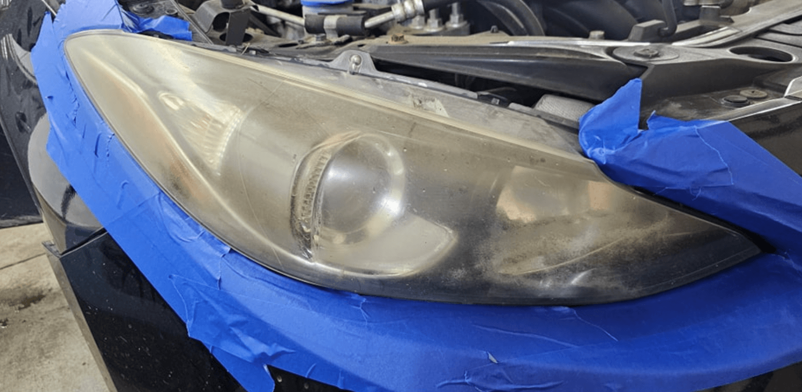 The headlight of a car is covered in blue tape.
