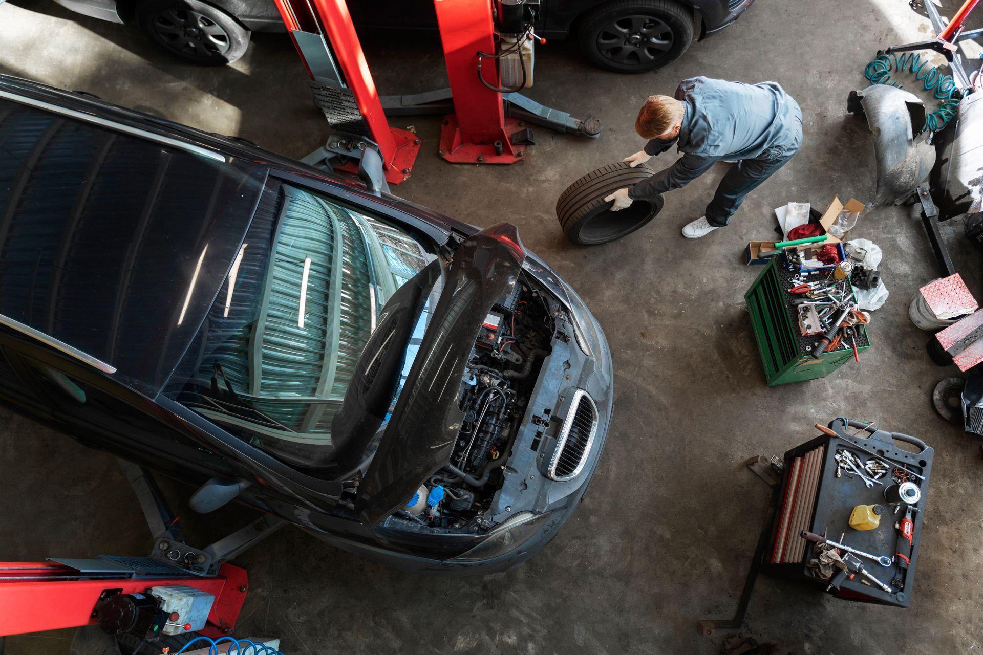A man is changing a tire on a car in a garage.