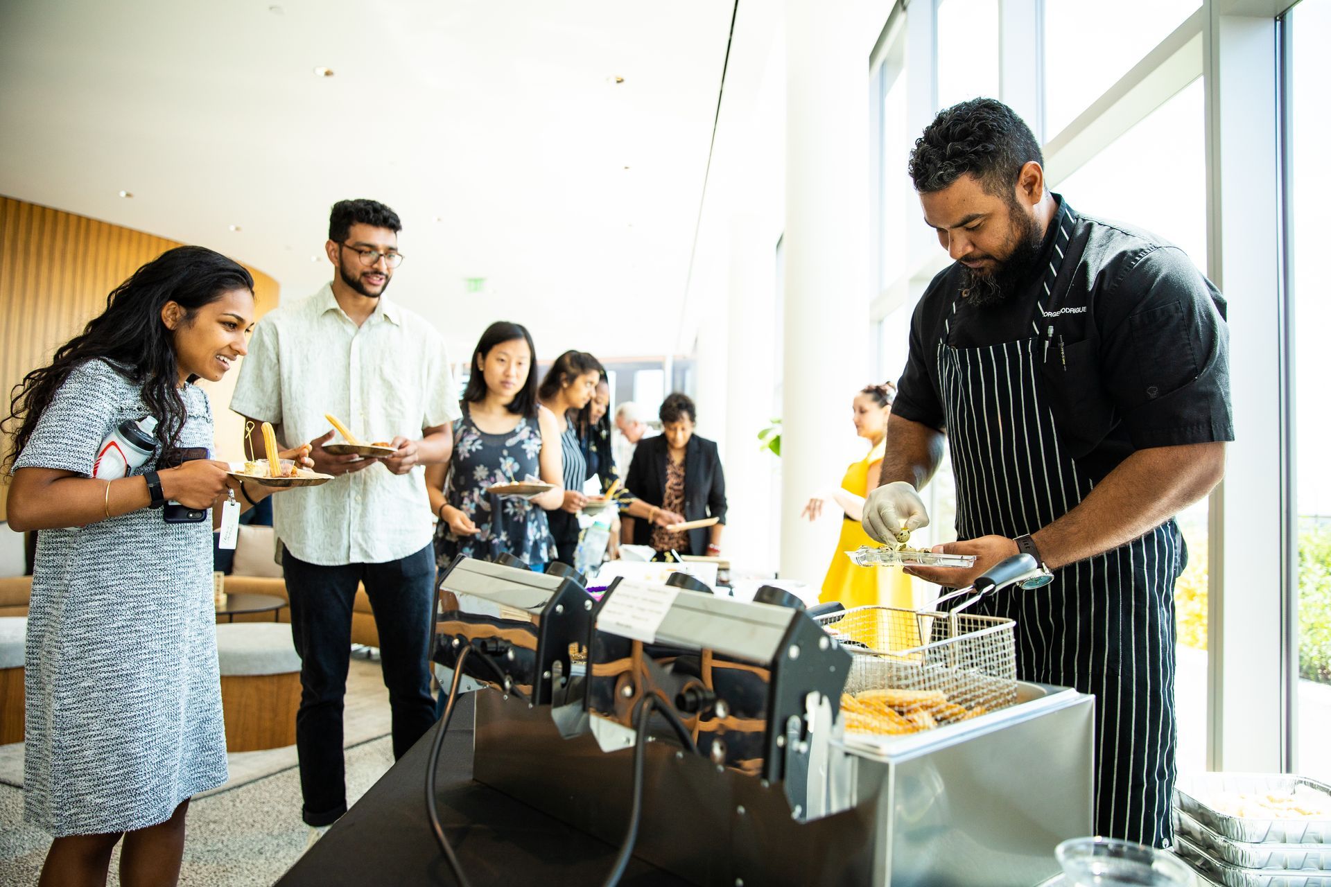 A man is serving food to a group of people at a buffet.