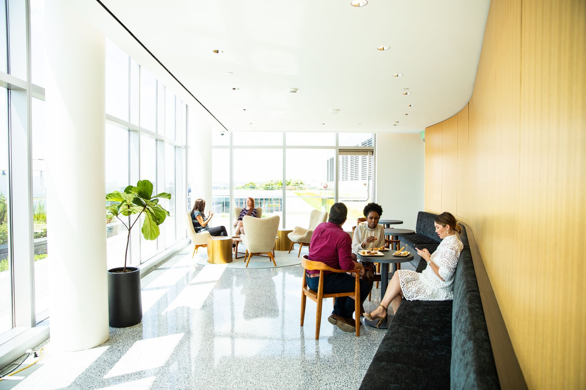 A group of people are sitting at tables in a lobby.