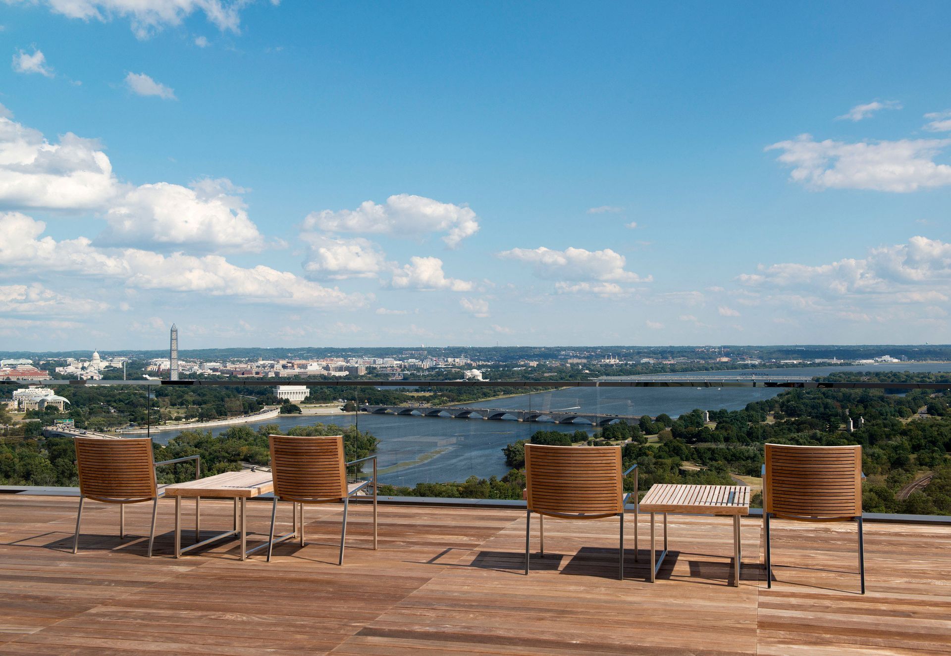 A wooden deck with chairs and tables overlooking a body of water.