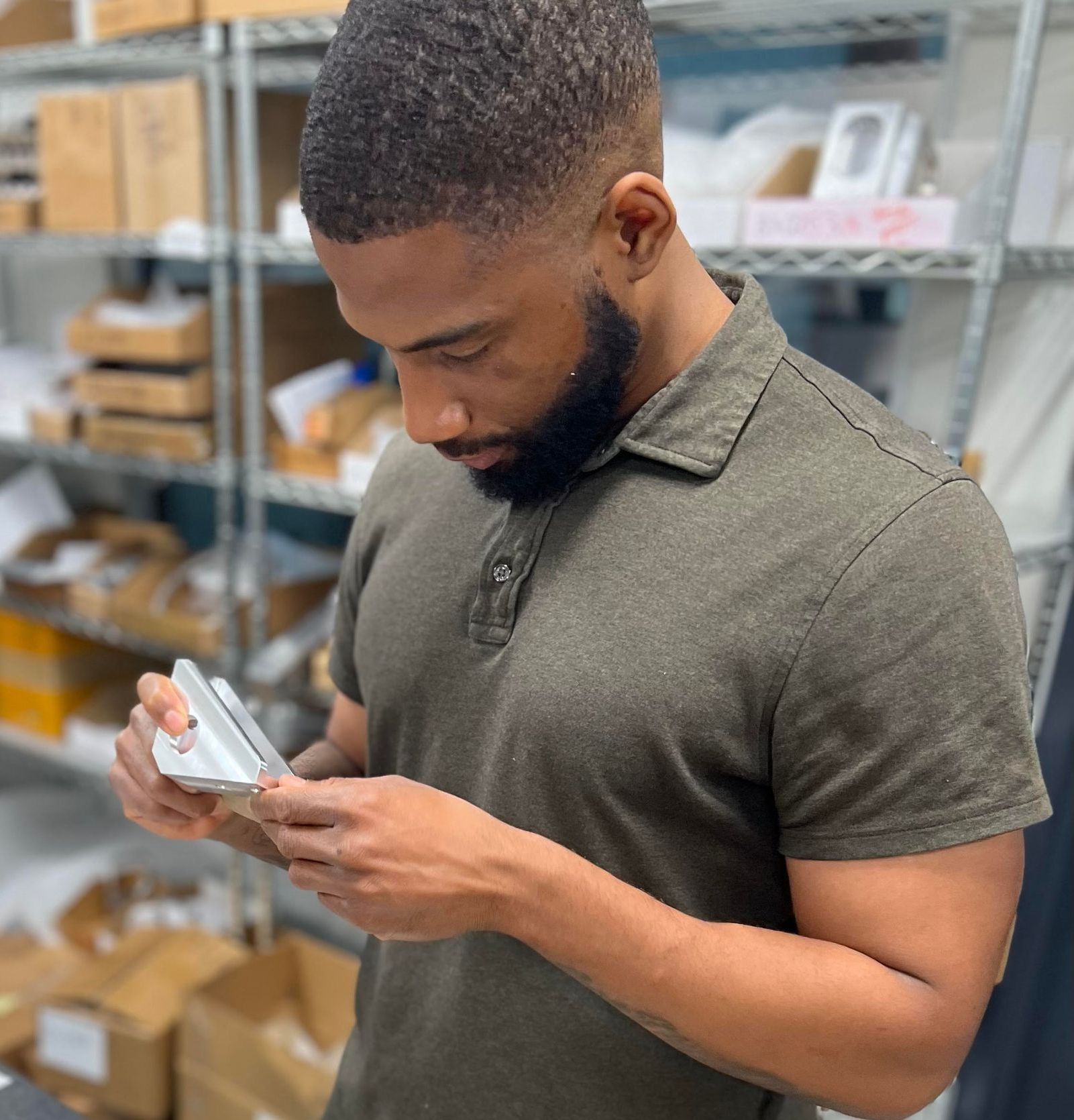 A man with a beard is looking at his phone in a store