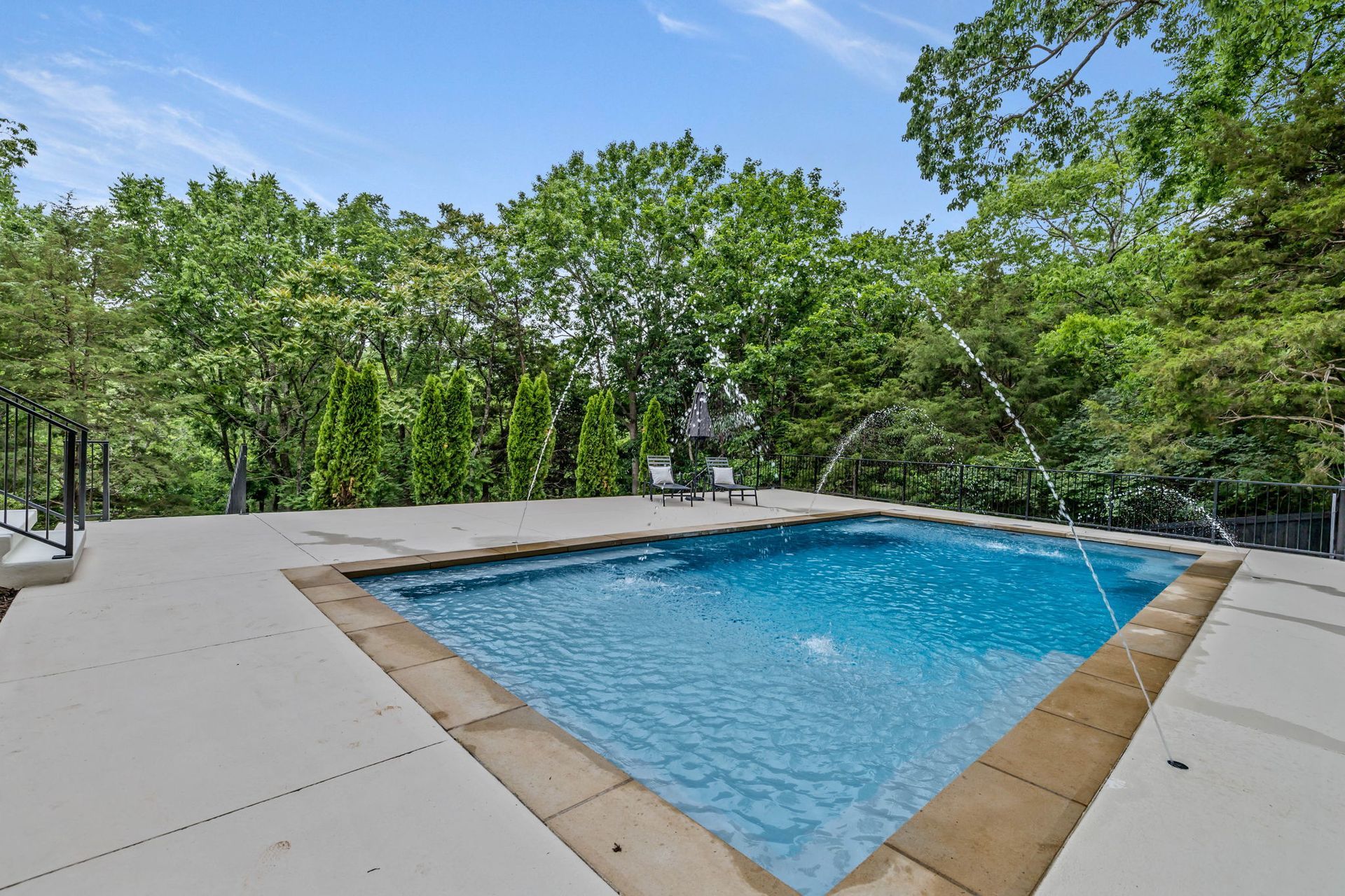 A large swimming pool is surrounded by trees and a deck.