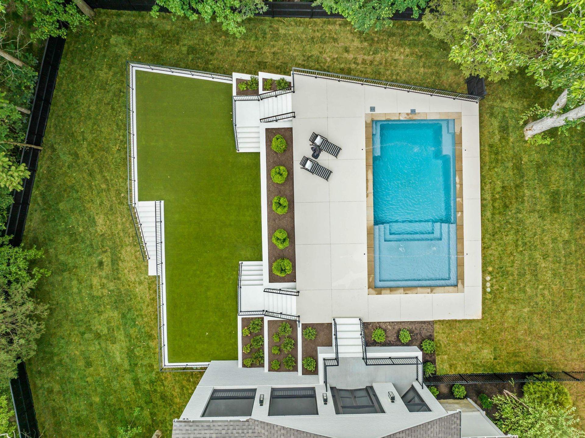 An aerial view of a house with a large swimming pool in the backyard.