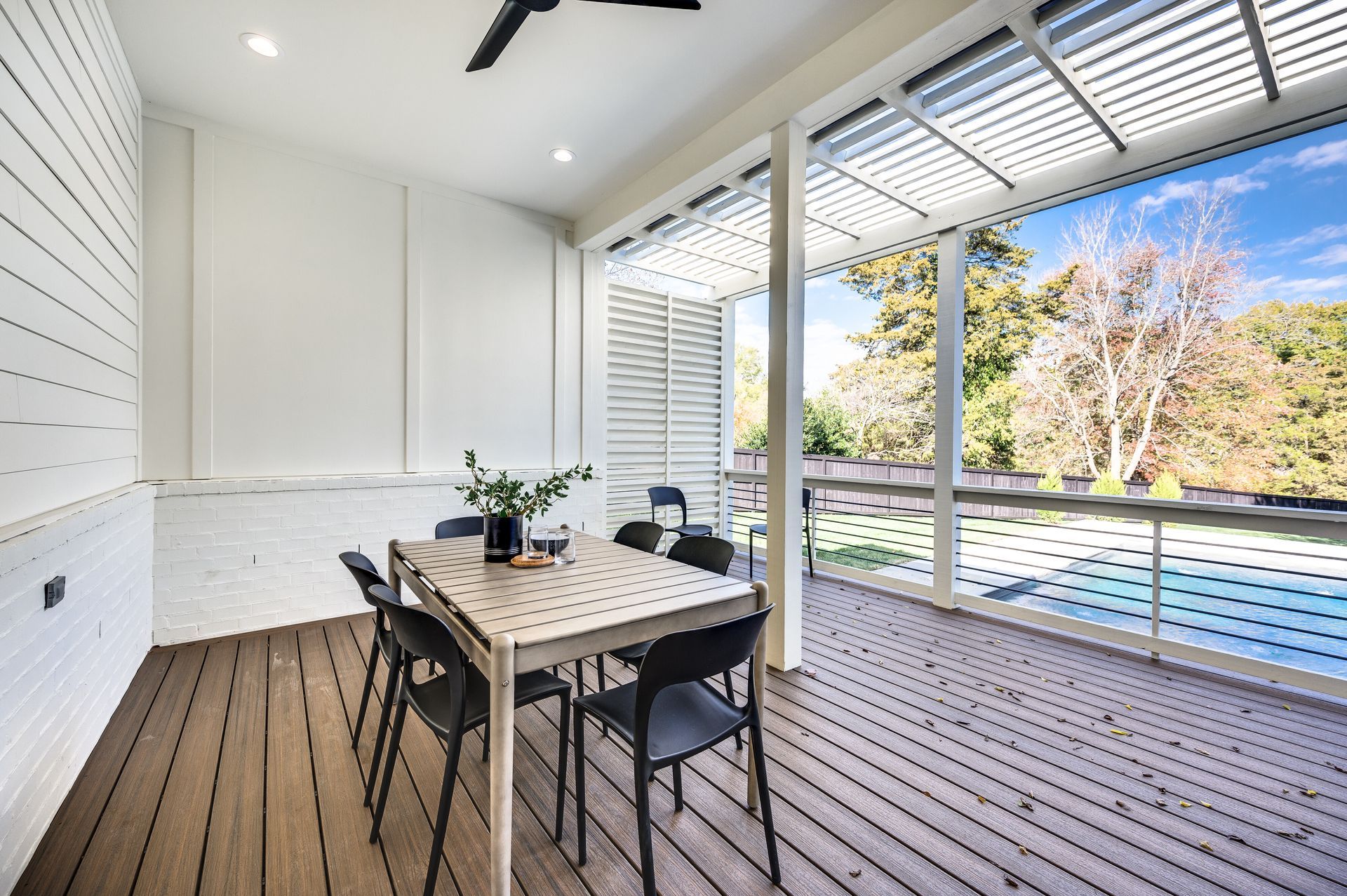 A patio with a table and chairs and a ceiling fan.