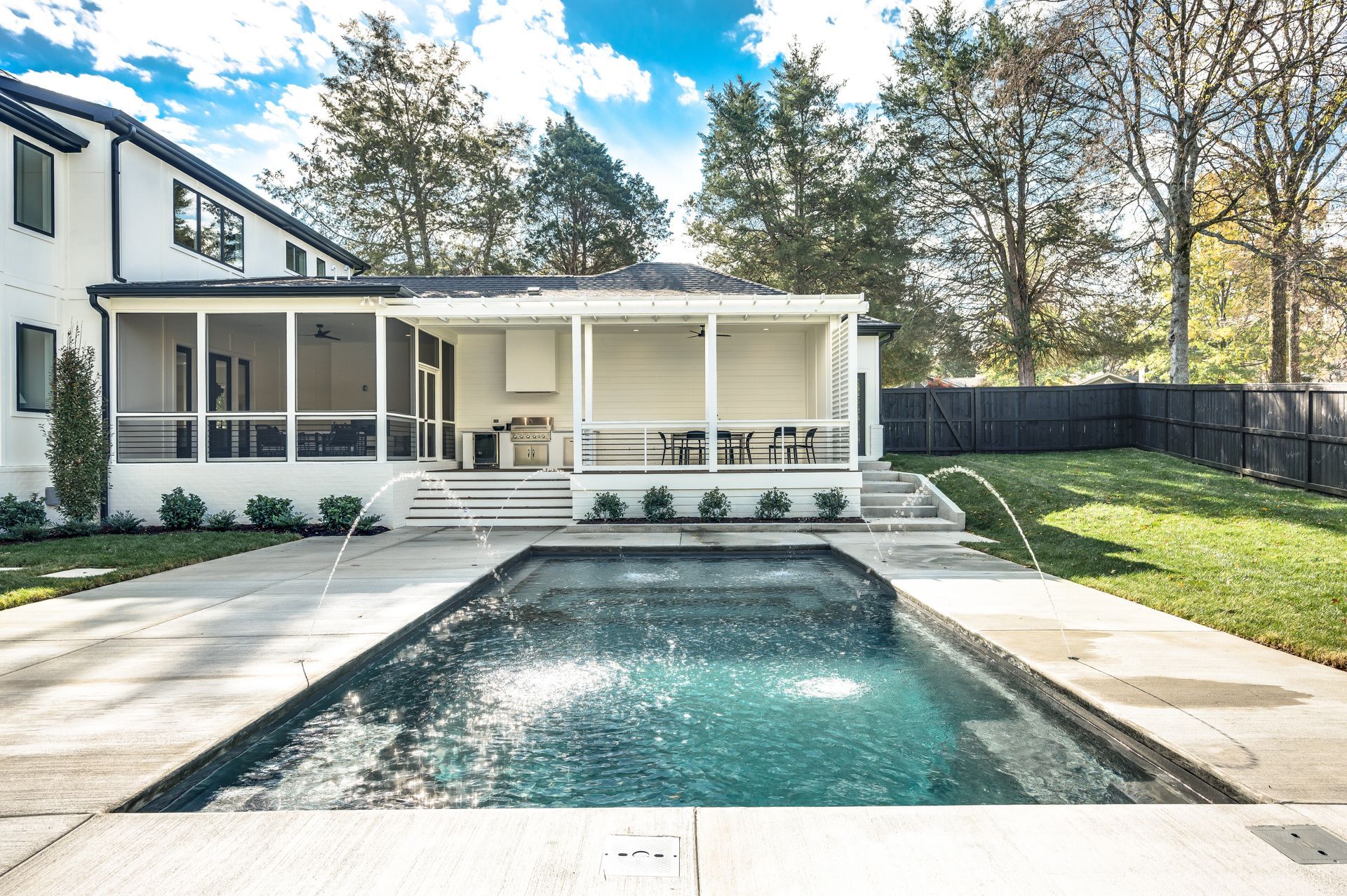 A large swimming pool is in the backyard of a house.