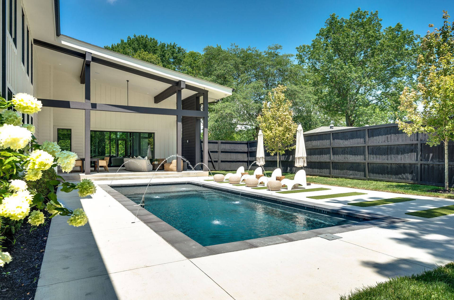 There is a large swimming pool in the backyard of a house.
