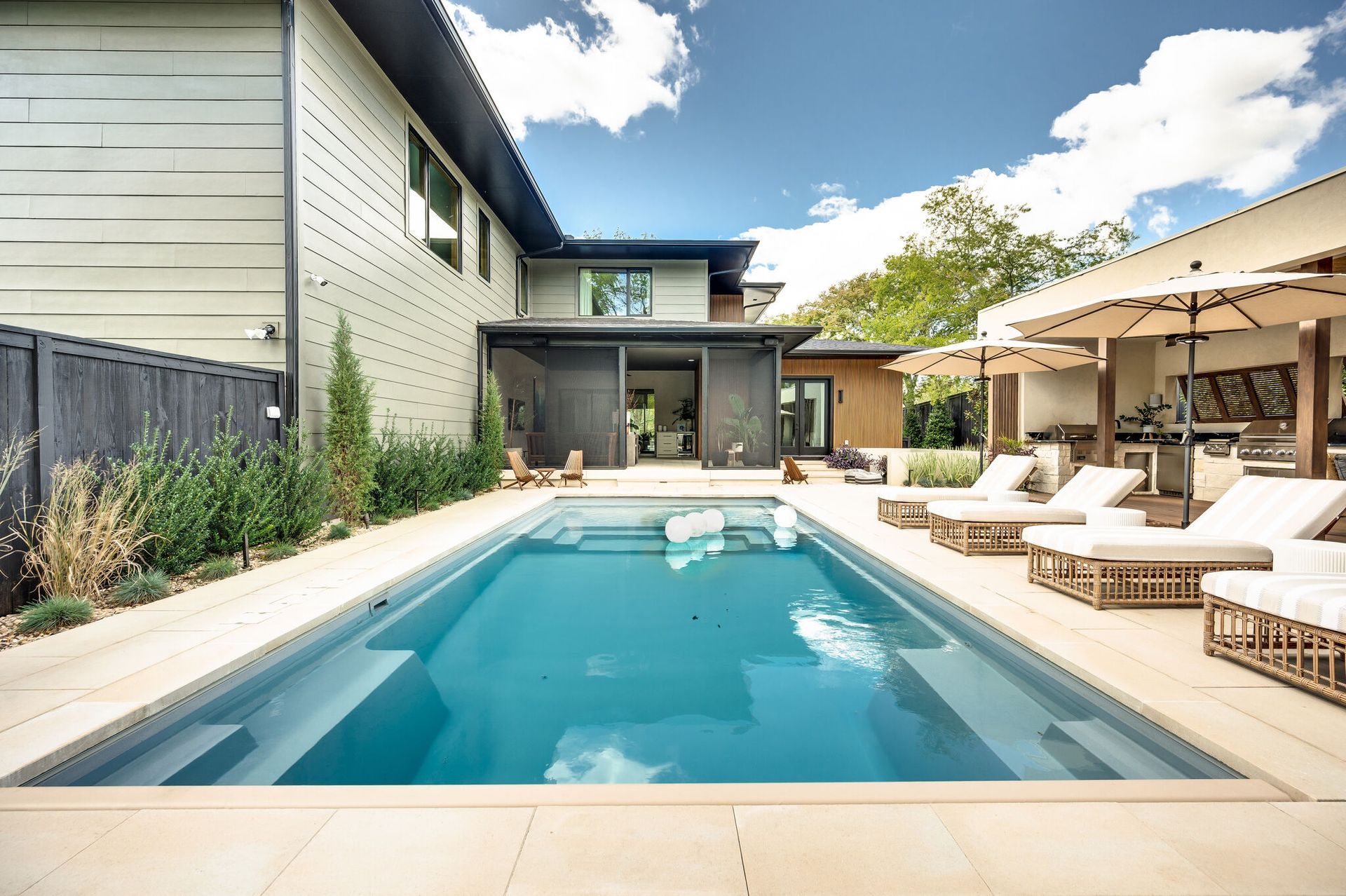 There is a large swimming pool in the backyard of a house.