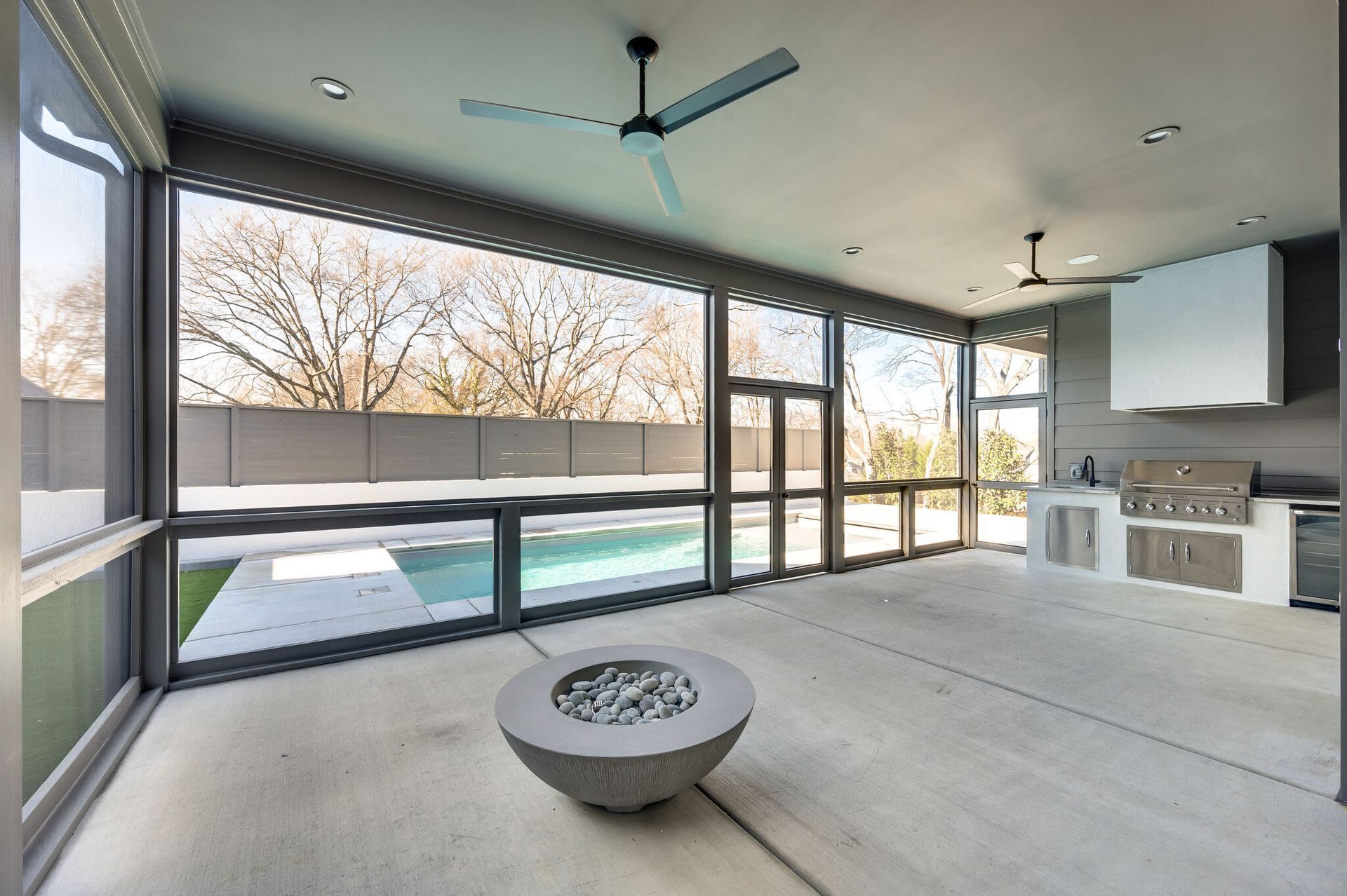 A screened in porch with a fire pit and a ceiling fan