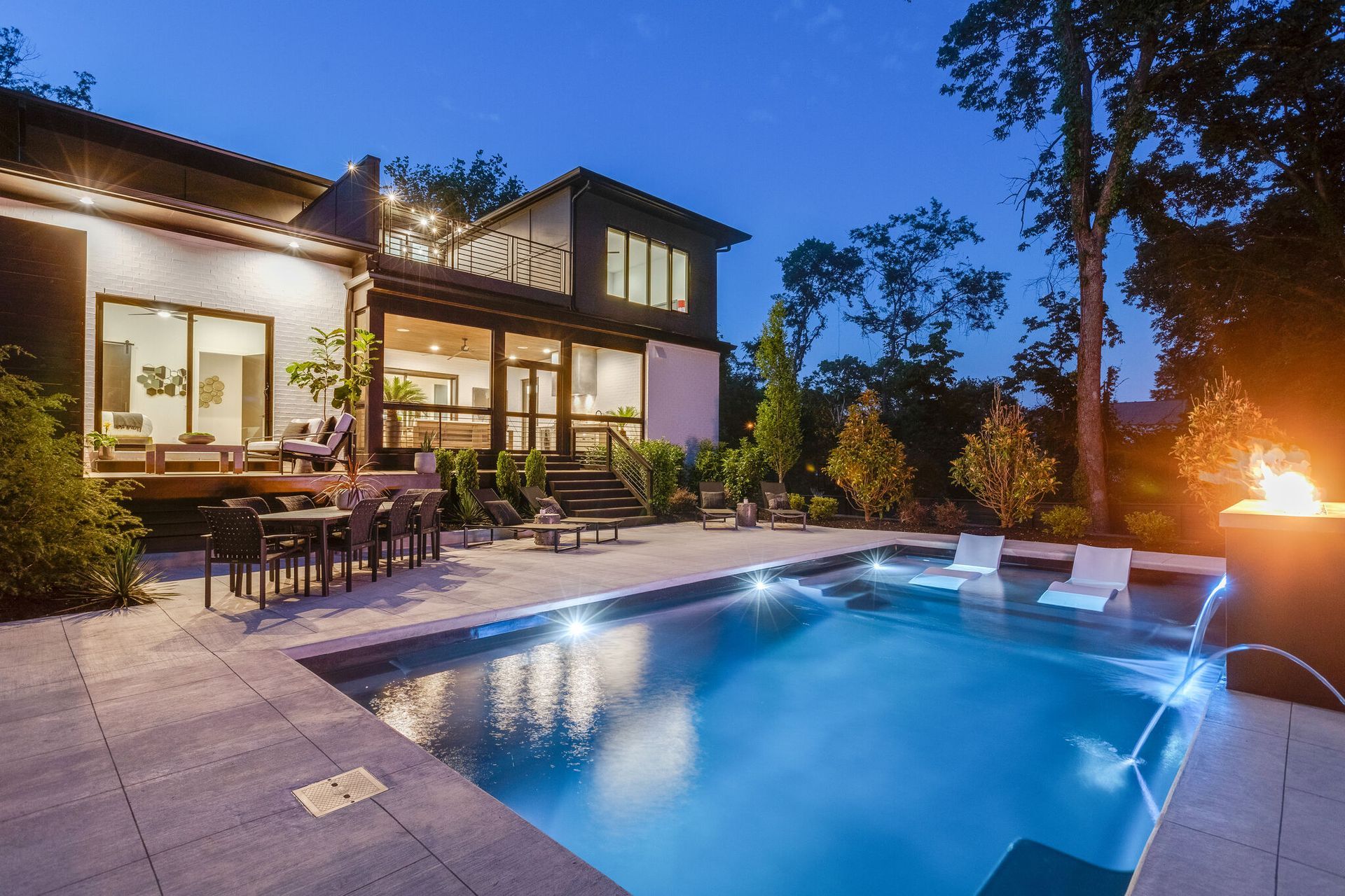 A large swimming pool is in the backyard of a house.
