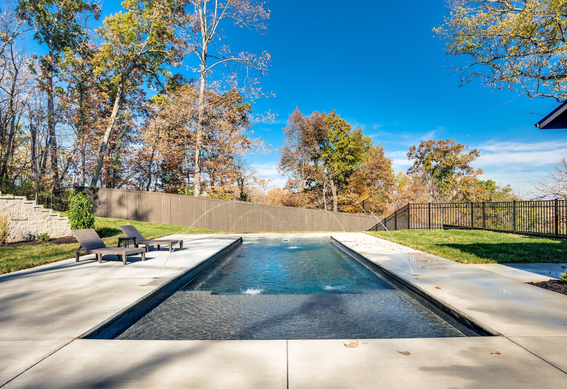 There is a large swimming pool in the backyard of a house.