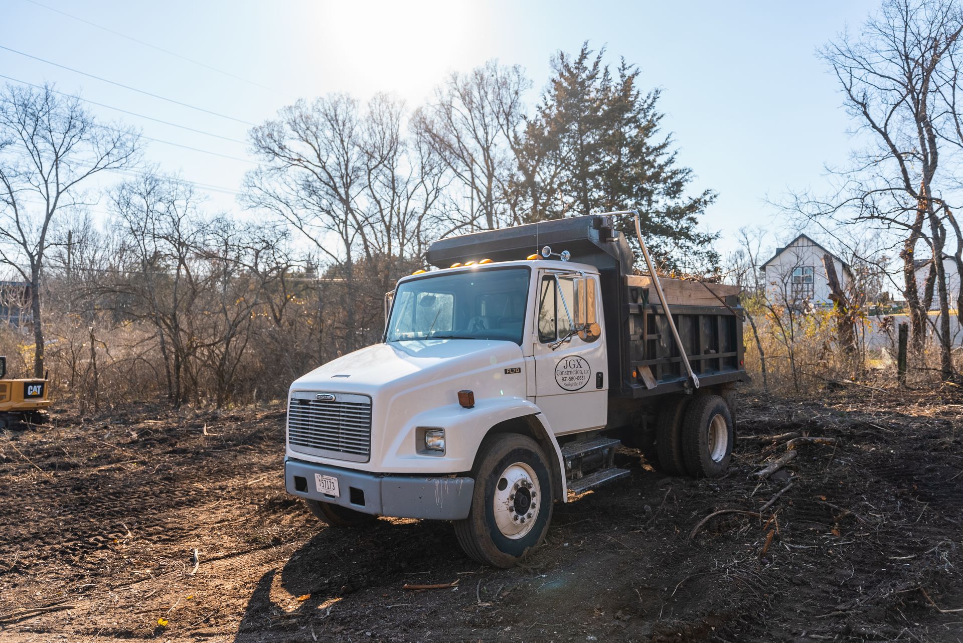 A white dump truck is parked in a dirt field.