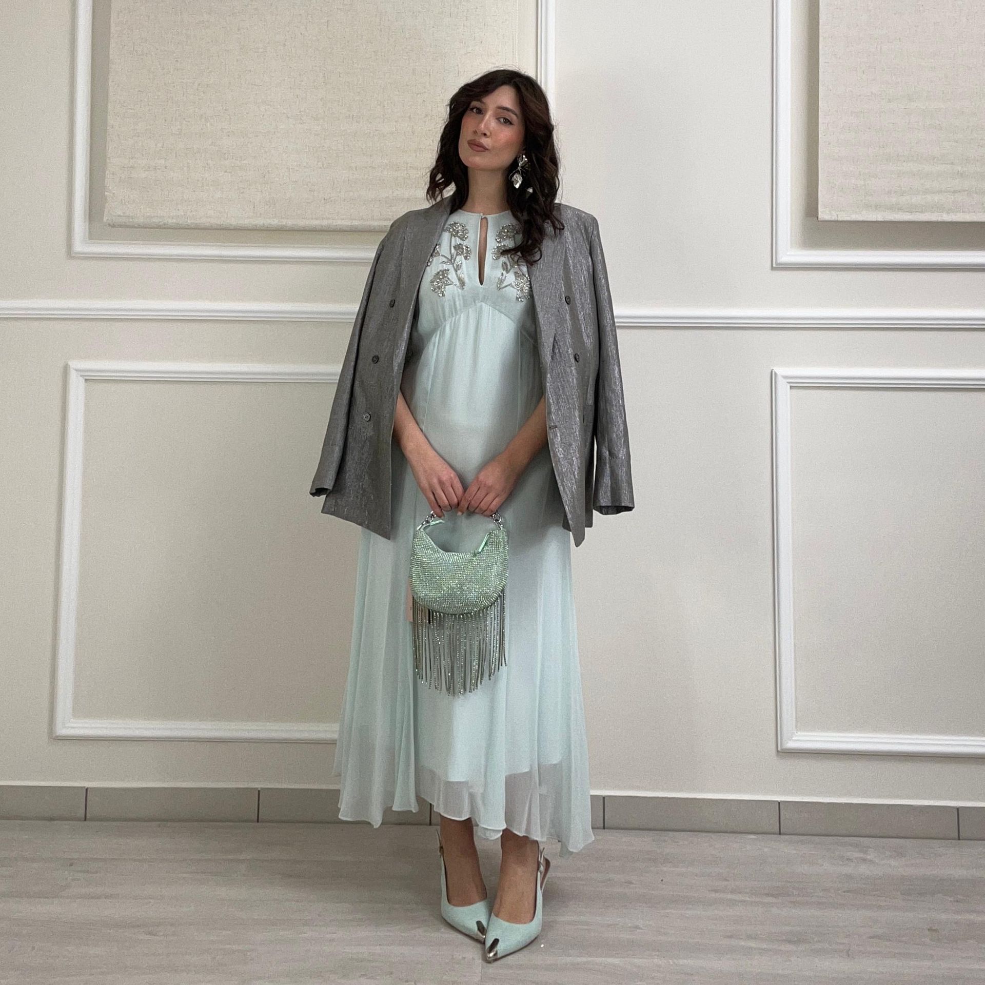 Una donna con un abito blu con paillettes è accovacciata su uno specchio.