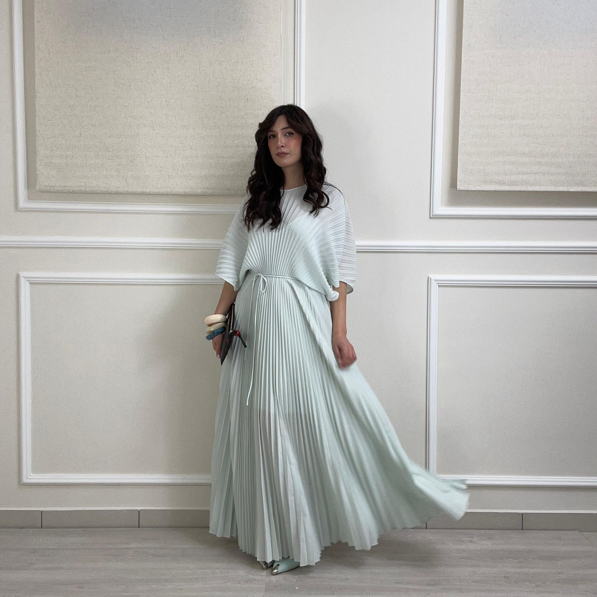 Una donna con un abito blu con paillettes è accovacciata su uno specchio.